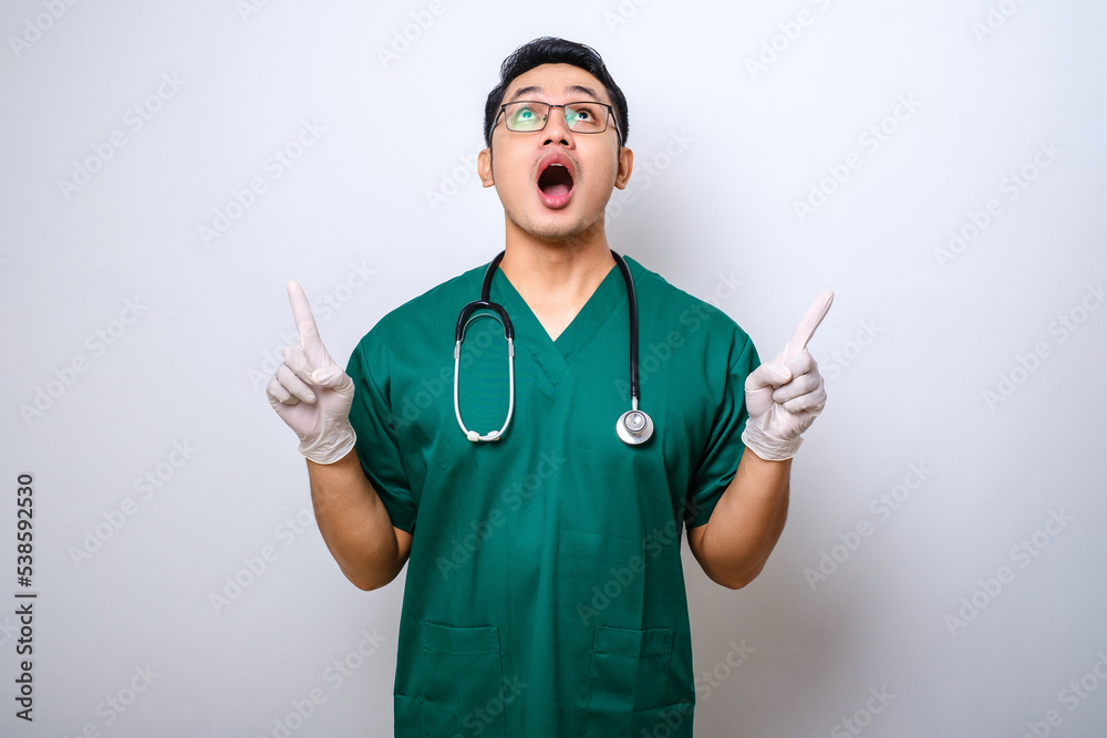 Surprised or curious male nurse in green scrubs, pointing fingers up, inform patients how prevent corona infection Surprised or curious male nurse in green scrubs, pointing fingers up, inform patients how prevent corona infection