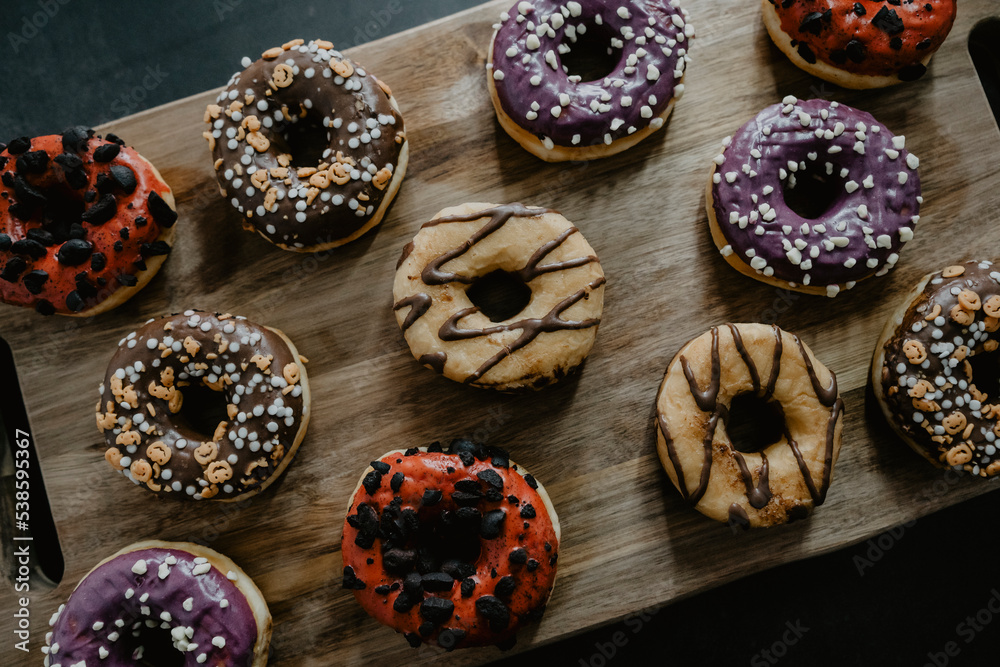 conjunto de donuts de diferentes colores con chocolate y azúcar encima de una tabla de madera conjunto de donuts de diferentes colores con chocolate y azúcar encima de una tabla de madera