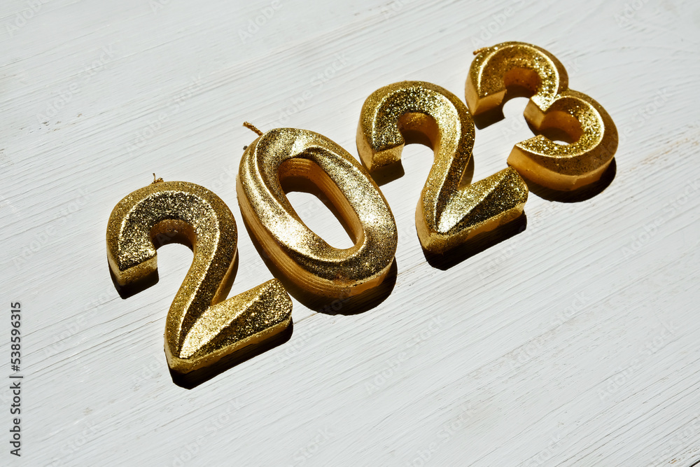 Festive background Happy New 2023 year. Golden sparkling numbers 2023 on a white wooden background. Side view, close-up. Festive background Happy New 2023 year. Golden sparkling numbers 2023 on a white wooden background. Side view, close-up.
