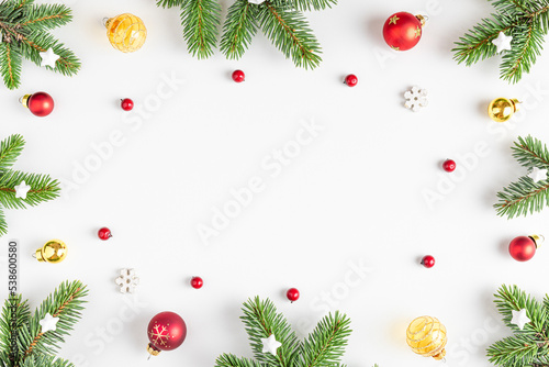 Christmas composition. Frame made of fir tree, festive decorations, red berries on white background. Flat lay