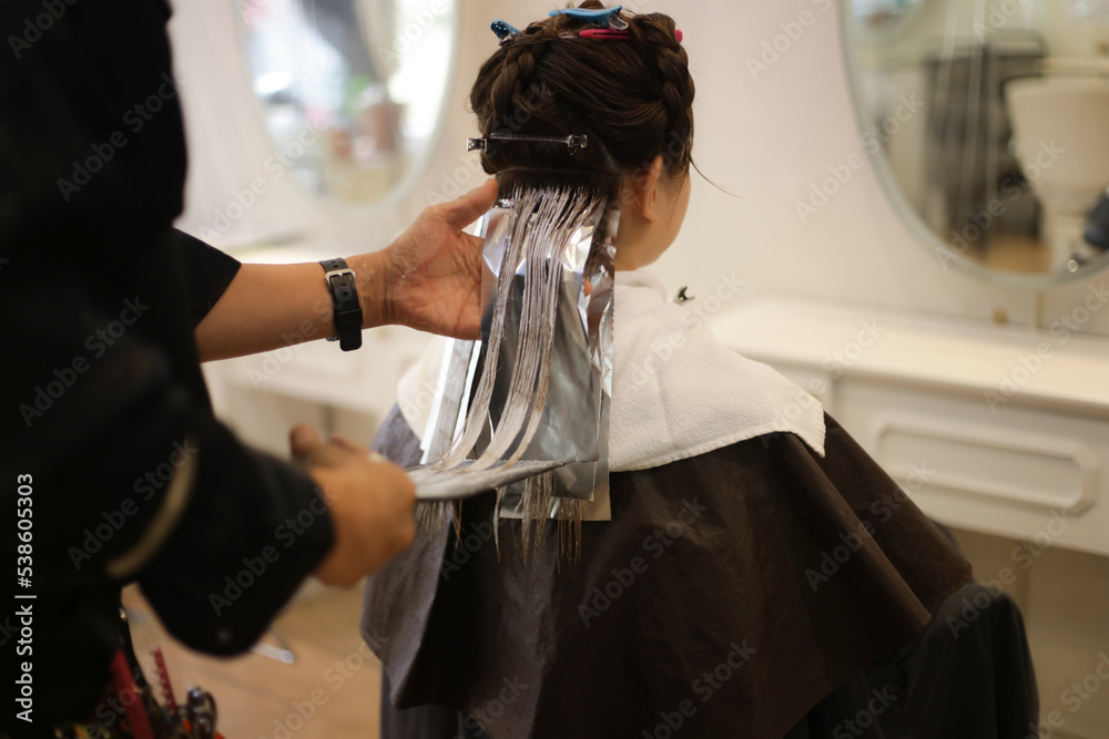 女性の髪のカラーリングをする男性美容師