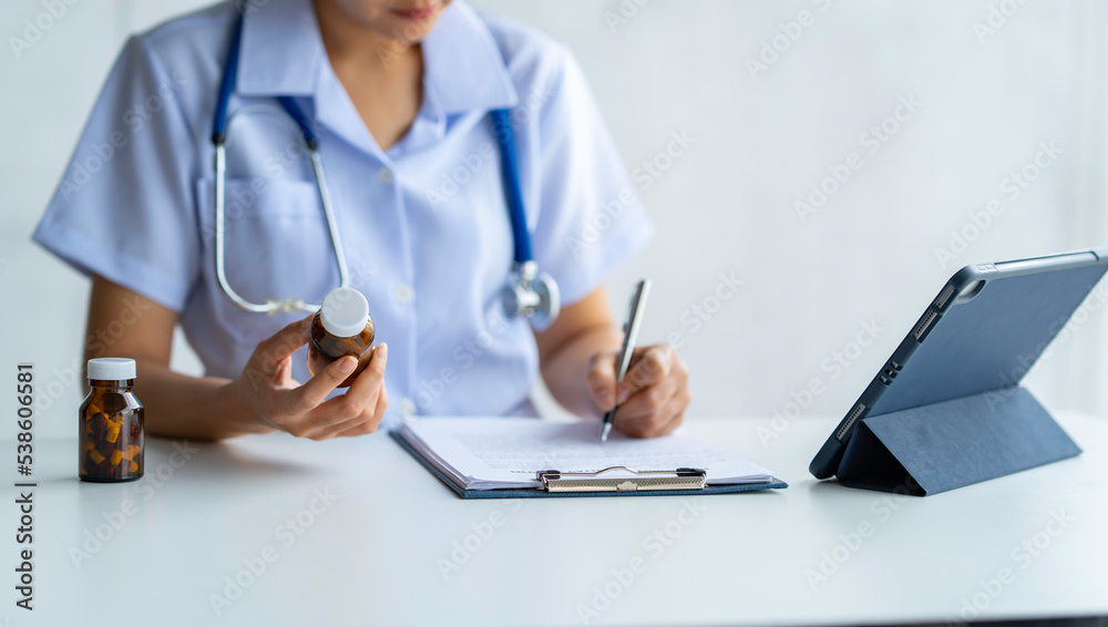 The female doctor looked at the information from the pill bottle and wrote down the details of the medication on a piece of paper. The female doctor looked at the information from the pill bottle and wrote down the details of the medication on a piece of paper.