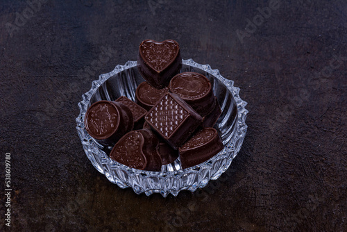 Chocolates on carved glass tray, photographed on a dark background.