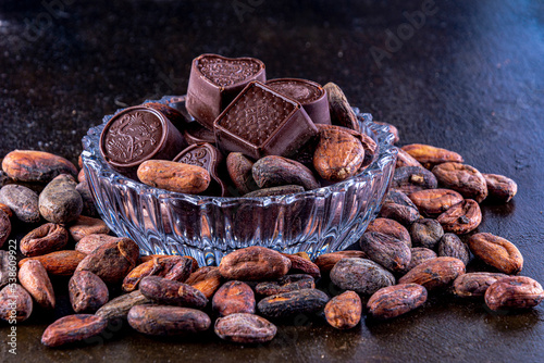 Chocolates on carved glass tray, photographed on a dark background with cocoa beans.