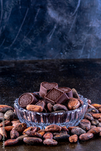 Chocolates on carved glass tray, photographed on a dark background with cocoa beans. © AlvaroRT