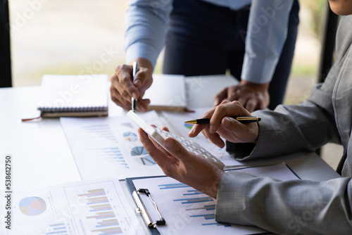Business executives analyze data documents and calculating about fee tax at an office Image of business people working together analyzing calculations using a laptop calculator and graph