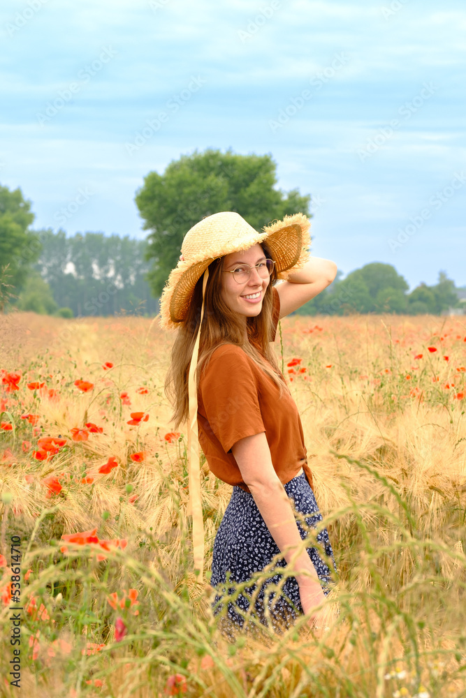 Young woman surround with poppies in a field of harvest-ready corn
