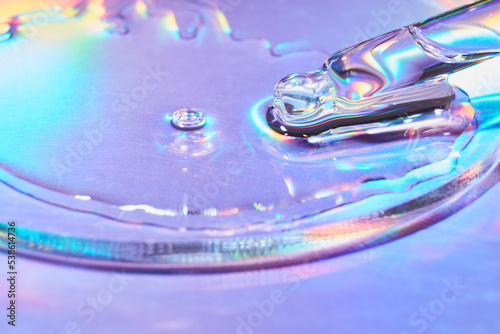 Pipette with sample of cosmetic product in petri dish on holographic background, iridescent highlights, selective focus