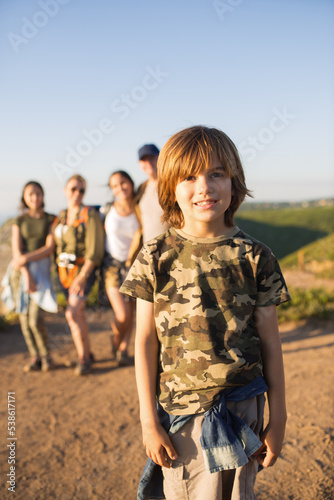 Portrait of happy little boy posing against family. Preteen child hiking with family in summer. Childhood and family weekend concept
