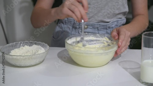 A girl of Caucasian appearance prepares a culinary product, mixes the dough.