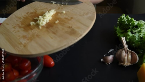 Hands chop garlic for Italian salad