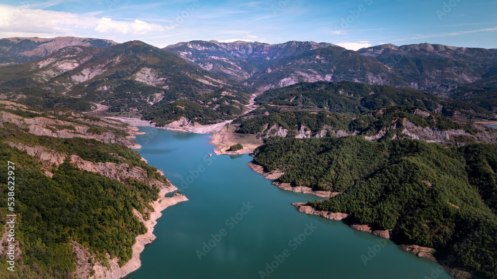 Fototapeta premium The water reservoir Lake Bovilla surrounded by mountains, blue sky, in Albania