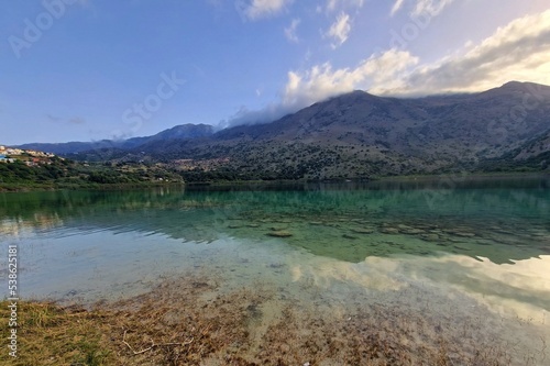 View of beautiful Kournas lake with clear turquoise water during sunset. Reflection of sun in water of Kournas lake during sunset © Hamik