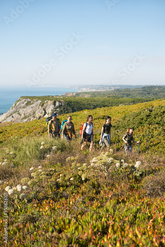 Happy family of five hiking in mountains in summer. Parents with children trekking outdoors. Active family weekend concept