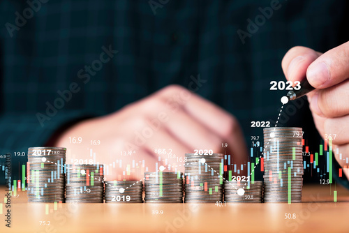 Businessman hand drawing virtual increasing graph with money coins stacking , Business investment profit and deposit dividend saving growth concept.