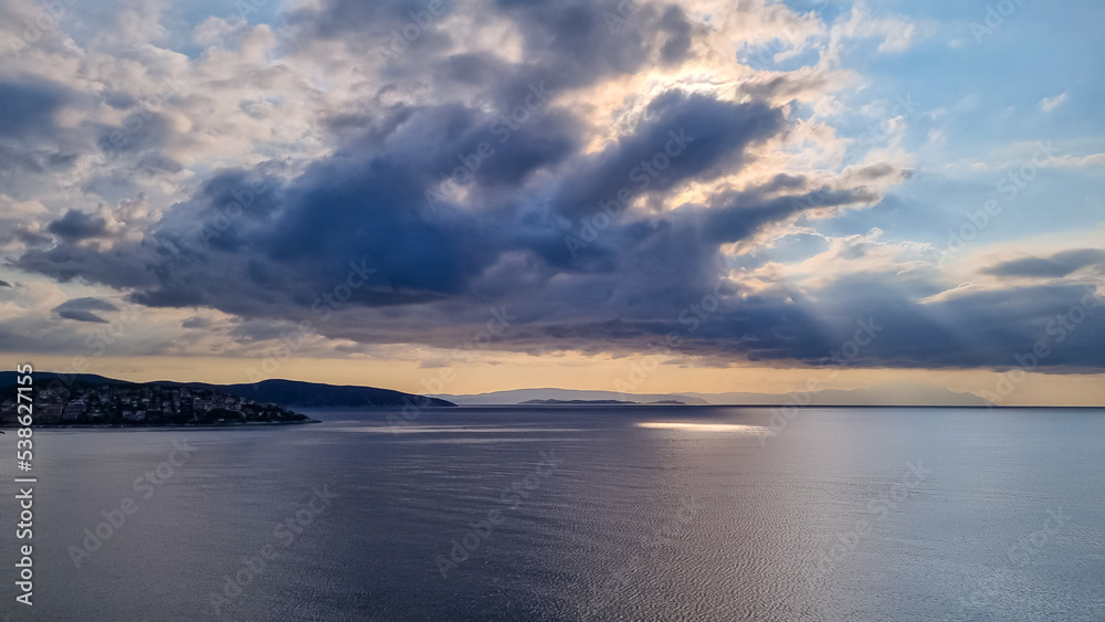Early morning view of the sunrise over the Mediterranean Aegean Sea. View on the peninsula Mount Athos (Again Oros), Chalkidiki, Central Macedonia, Greece, Europe. Sun beams on the water surface, calm