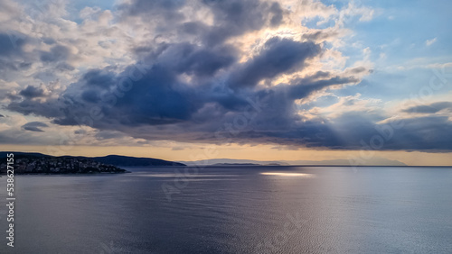 Early morning view of the sunrise over the Mediterranean Aegean Sea. View on the peninsula Mount Athos (Again Oros), Chalkidiki, Central Macedonia, Greece, Europe. Sun beams on the water surface, calm