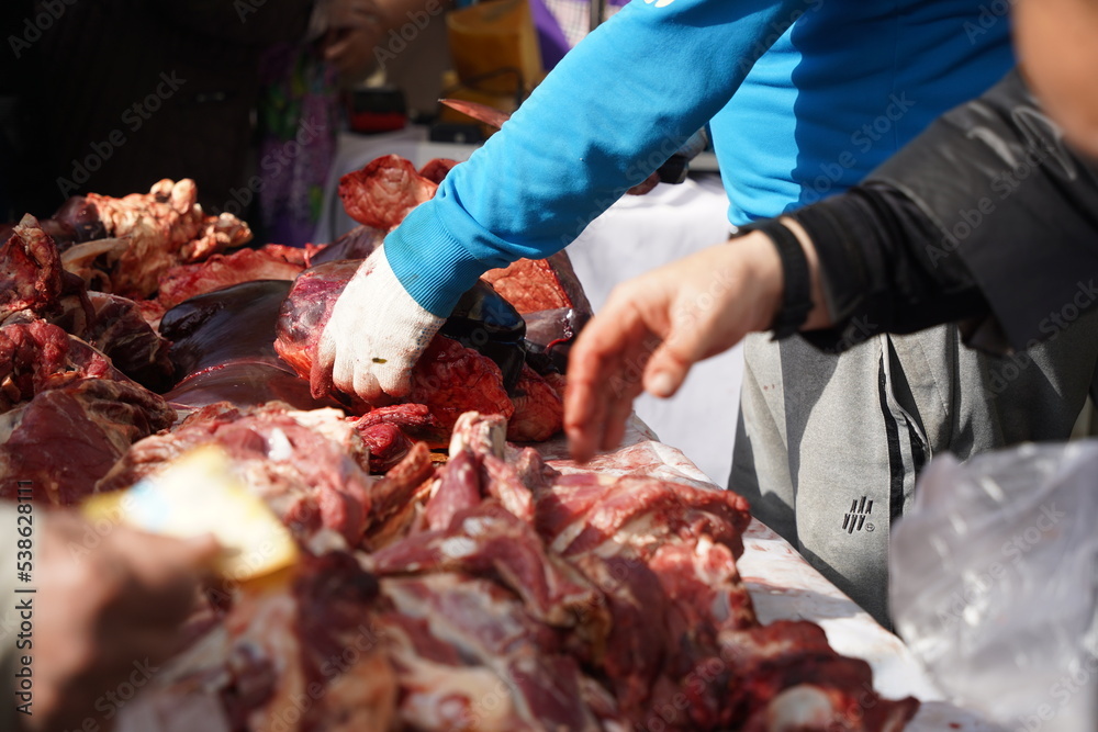 Almaty, Kazakhstan - 10.15.2022 : The seller chooses pieces of meat on the open market.