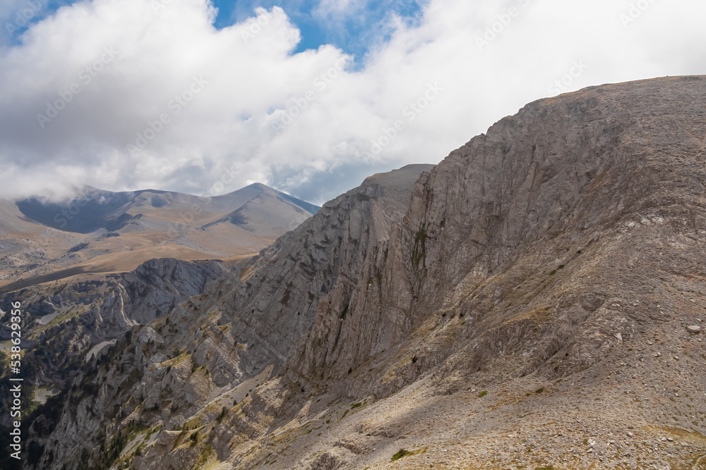 Panoramic view of the cloud covered slopes and rocky ridges of Mount Olympus (Mytikas, Skala, Stefani) in Mt Olympus National Park, Thessaly, Greece, Europe. Trekking on mystical hiking trail. Awe