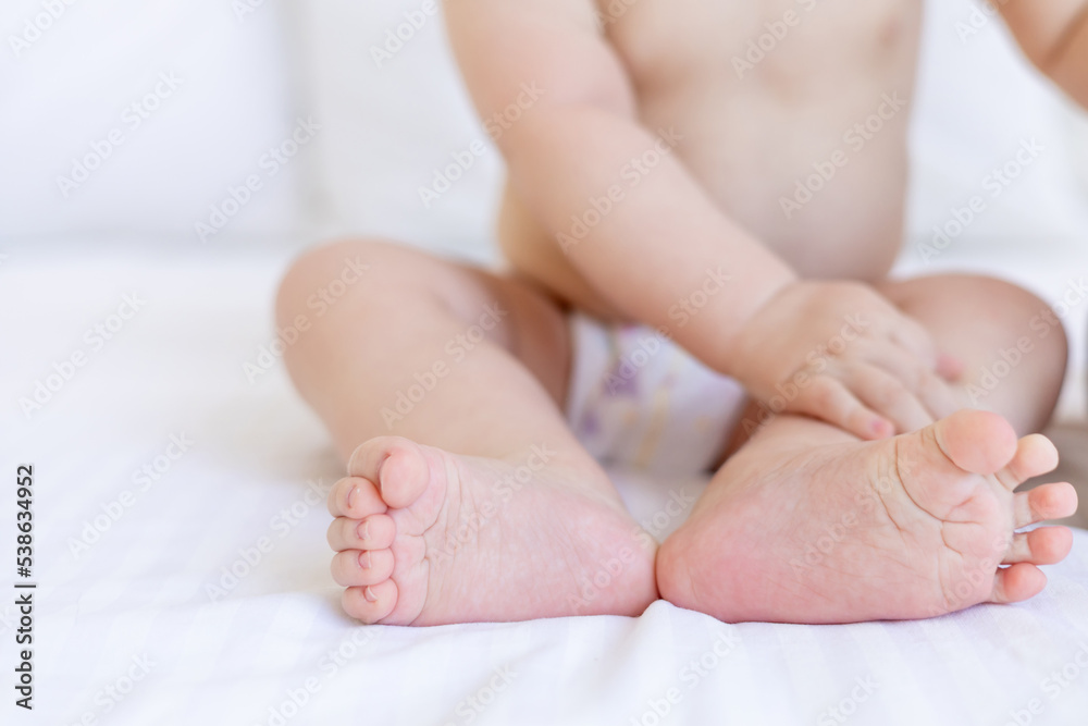 legs or feet of a six-month-old baby in close-up on a white cotton bed at home legs or feet of a six-month-old baby in close-up on a white cotton bed at home