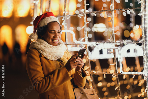 Black Woman Using Smartphone In The City At Christmas Time