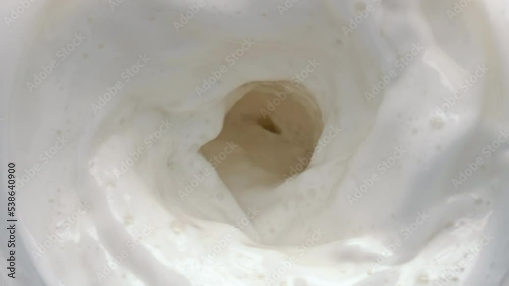 Lactose beverage swirling moving top view. Milk rotating with waves closeup