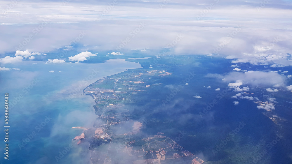 Cloudy. Beautiful sky with fluffy white cumulus clouds, nature, abstract background. View from the plane to the city sea and mountain landscape. Selective focus.