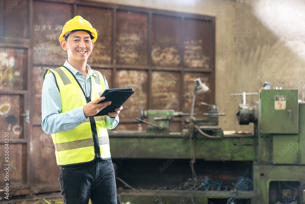 Industrial Engineers in Hard Hats.Work at the Heavy Industry Manufacturing Factory. Manual workers discussing while using smart phone at factory. Smiling and happy employee. Industrial Engineers in Hard Hats.Work at the Heavy Industry Manufacturing Factory. Manual workers discussing while using smart phone at factory. Smiling and happy employee.