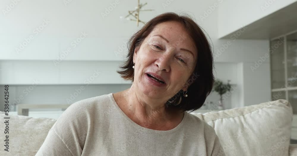 Head shot of older attractive smiling woman talk to family, enjoy conversation using video conference application. Distancing communication, older generation using modern tech for comfort life concept Head shot of older attractive smiling woman talk to family, enjoy conversation using video conference application. Distancing communication, older generation using modern tech for comfort life concept