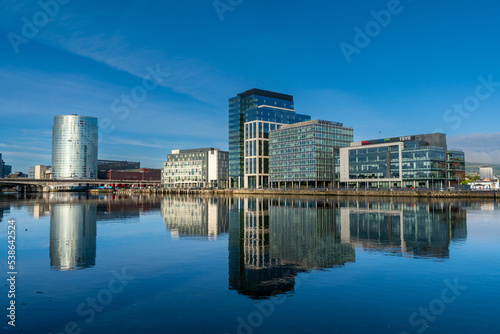 skyline of downtown Belfast with skyscrapers and reflections in the calm River Lagan at dawn