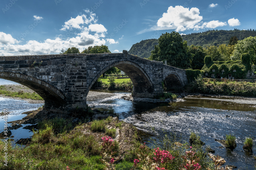 the historic Pont Fawr bridge and ivy-covered house on the River Conwy in North Wales