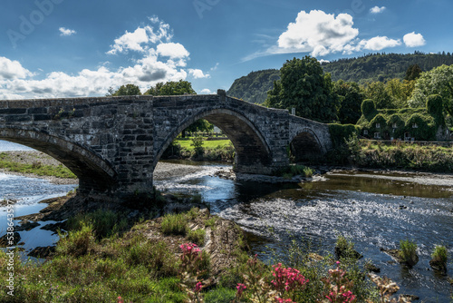 the historic Pont Fawr bridge and ivy-covered house on the River Conwy in North Wales photo