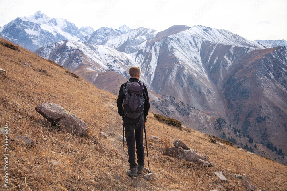 Young traveler with a backpack on the road enjoying view of the mountains.