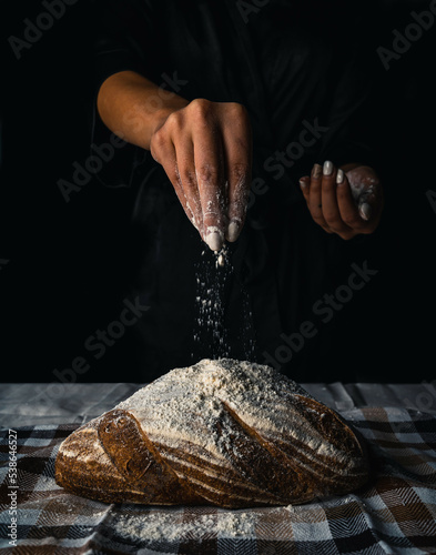 The female hands in flour and rustic organic loaf of bread