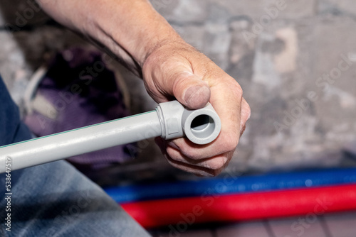 A worker, a plumber, holds a PVC pipe for water supply in his hand