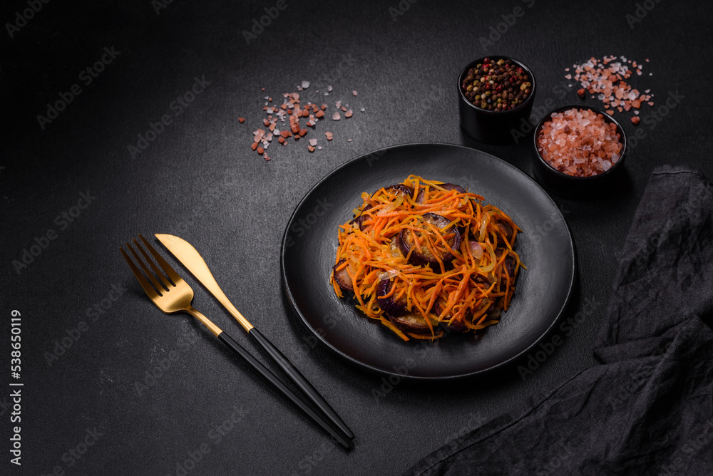 Korean salad with eggplant, carrots, garlic, spices and herbs on a dark concrete background Korean salad with eggplant, carrots, garlic, spices and herbs on a dark concrete background