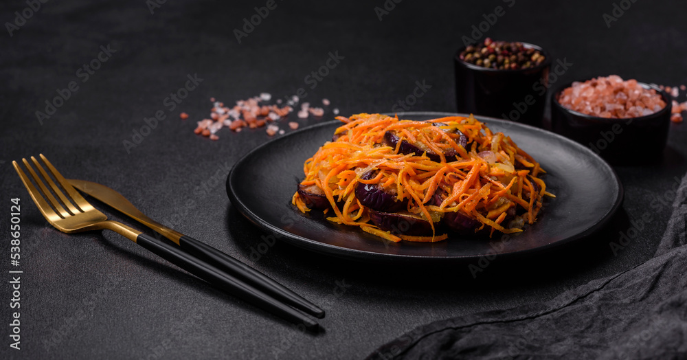 Korean salad with eggplant, carrots, garlic, spices and herbs on a dark concrete background