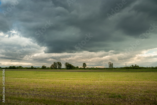 A stubble field and rainy clouds on the sky © darekb22