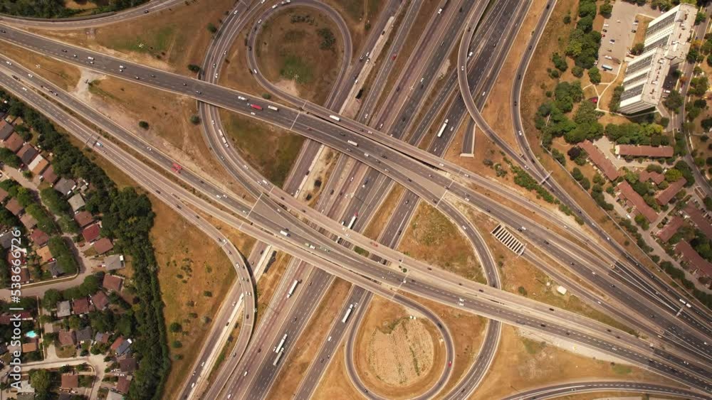 Top down aerial of cars drive across the expressway road in Canada. Cityscape and Highway. Transportation traffic at multilevel high speed road complex in North America. Top down aerial of cars drive across the expressway road in Canada. Cityscape and Highway. Transportation traffic at multilevel high speed road complex in North America.