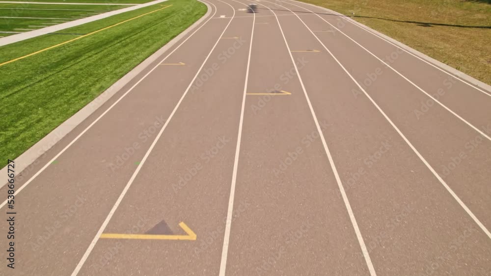 Over head view of running track at an outdoor sports stadium. Athlete POV of racing along athletic stadium and running track. Competition sports and champion hard workout.