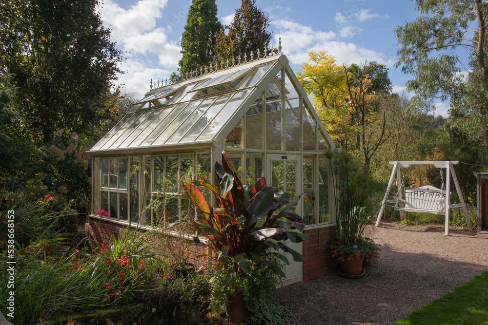 Greenhouse and garden swing sat in scenic garden Greenhouse and garden swing sat in scenic garden