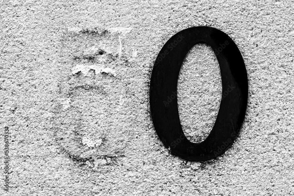 Address number Fifty on rough wall of a house with a peeling Five and a black Zero Address number Fifty on rough wall of a house with a peeling Five and a black Zero
