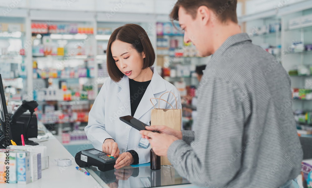 Obraz premium The doctor prescribes the pills according to the customer prescription.Business, pharmacy, professional health care.An adult customer stands to pay at the pharmacy counter.