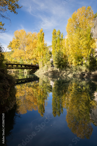 
The Jucar river in autumn in Cuenca, Castilla La Mancha in Spain. Autumn landscape with trees full of yellow leaves