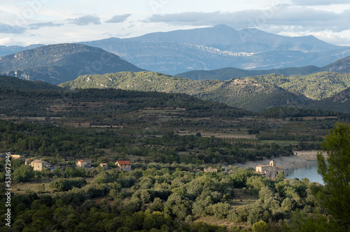 view over a village nestled in Parque natural de la Sierra y los Cañones de Guara, towards the Spanish Pyrenees mountains