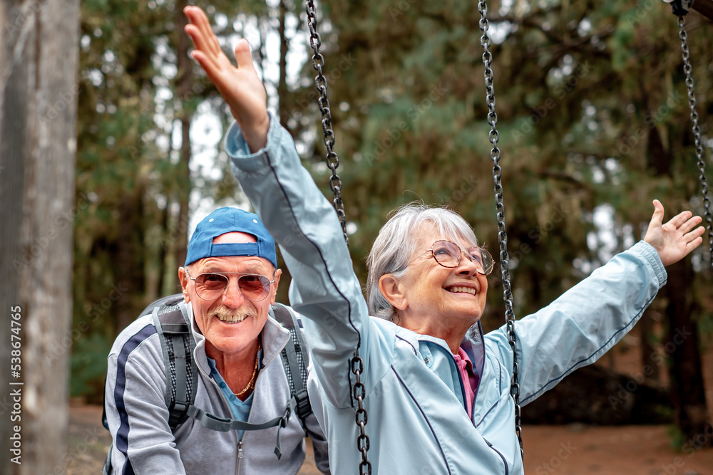 Obraz premium Happy senior couple in mountain picnic area enjoying with swing like children, enjoying healthy lifestyle in nature