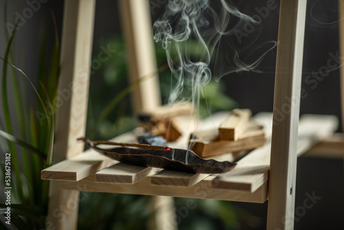 magical smoke from a burning incense stick on an incense stand on a wooden shelf in the interior Concept of mental health