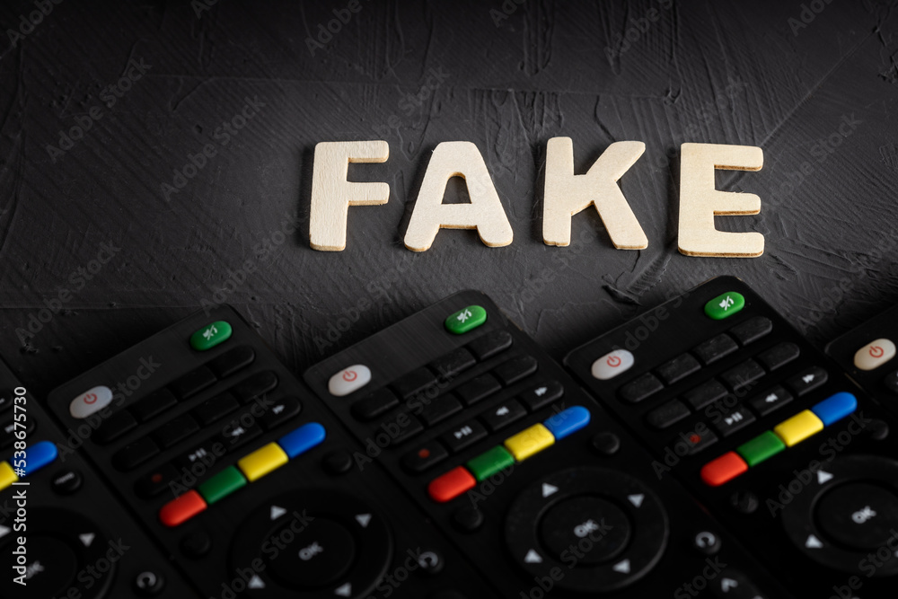 the word fake is made of wooden letters on a dark background