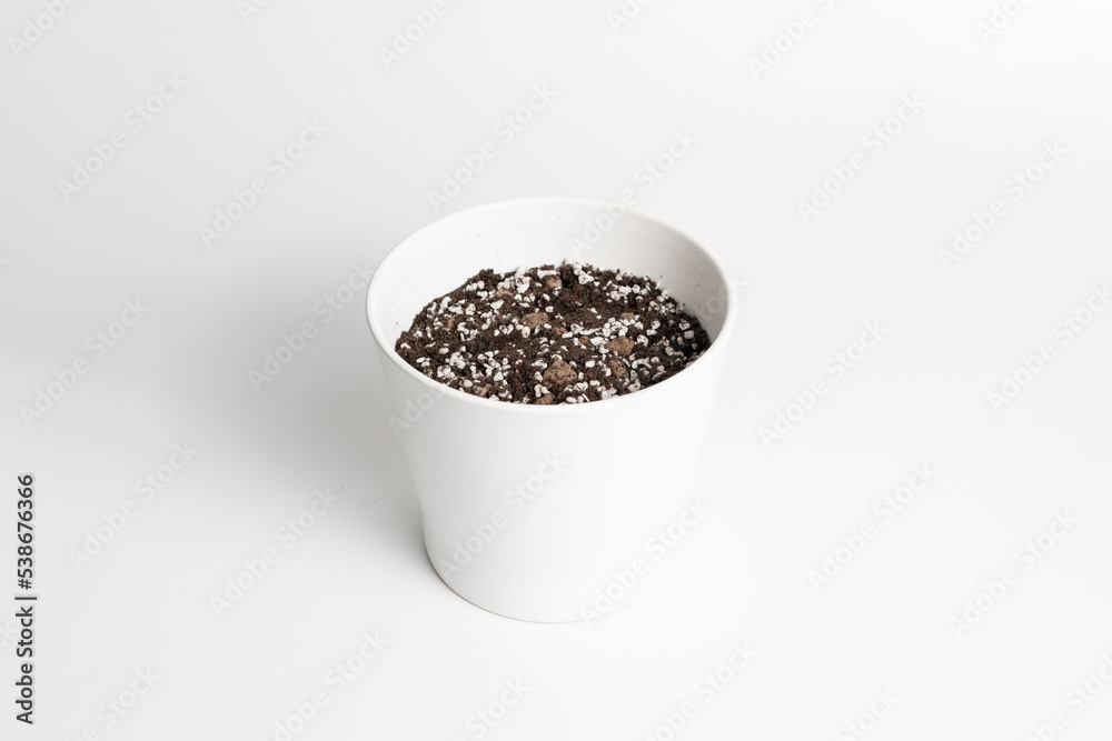 White ceramic pot with porous soil mixture in isolated white background. White ceramic pot with porous soil mixture in isolated white background.