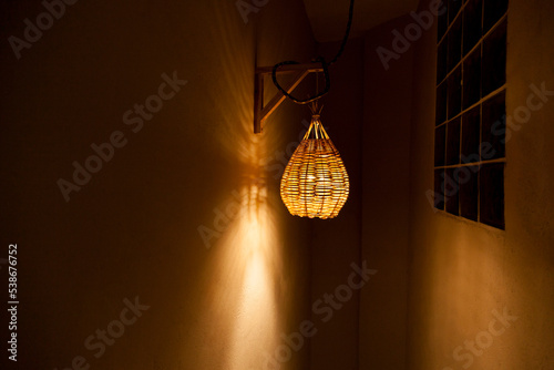 Pendant luminaire for outdoor area with yellow light. Handmade lamp made of straw. Luminaire concept. Home sweet home concept.